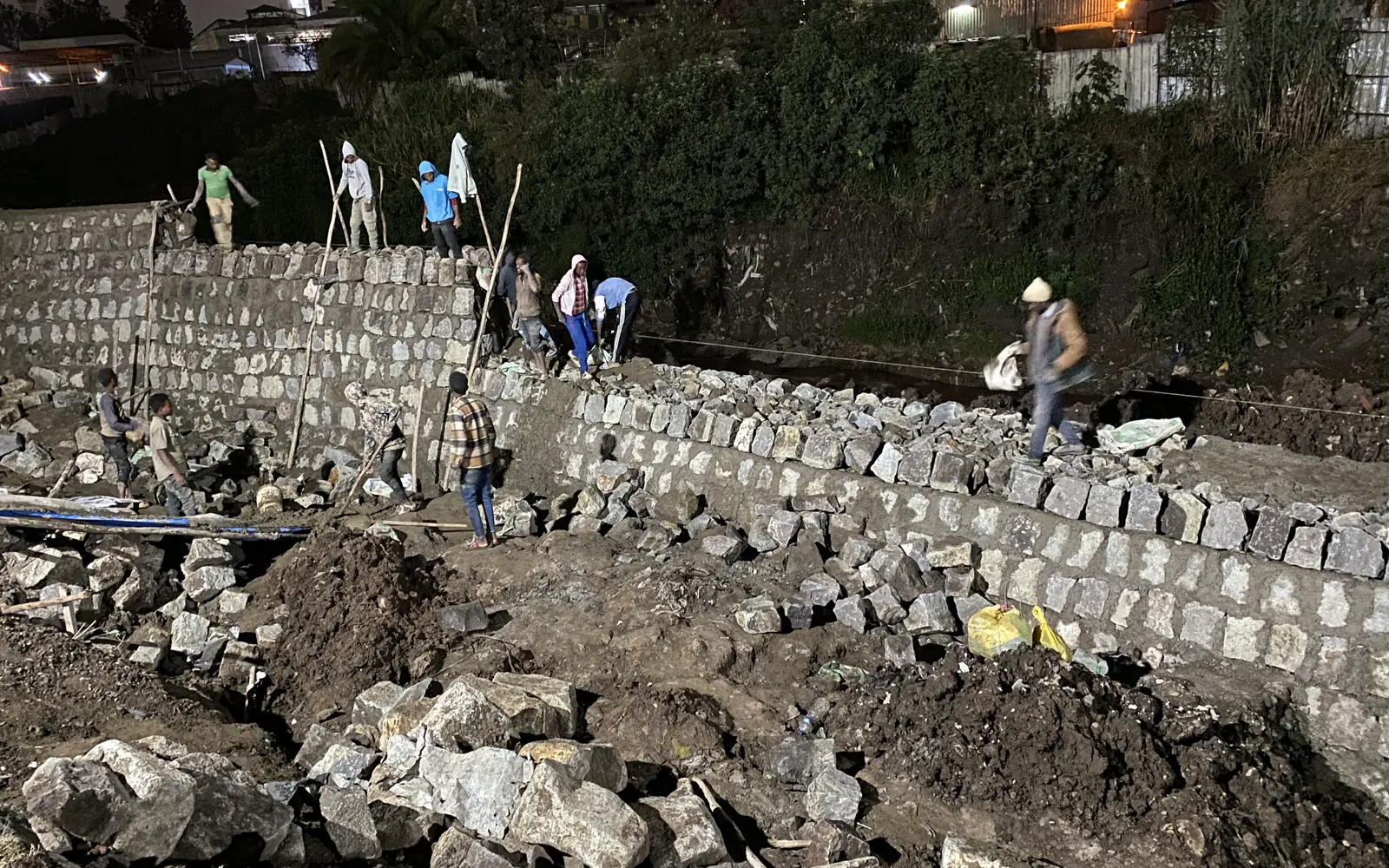 Masonry crew building a stone retaining wall at night
