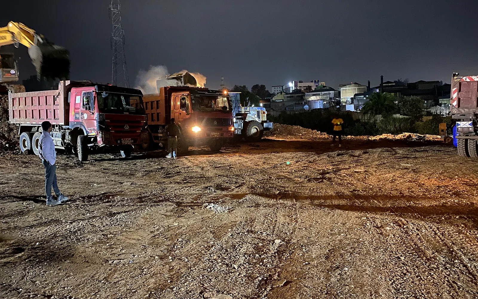 Earthmoving equipment and dump trucks coordinating work at night