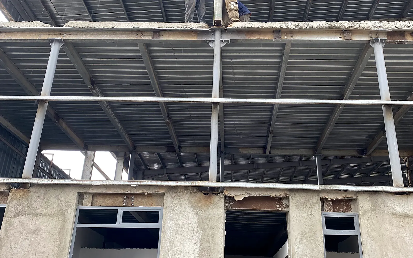 Construction crew installing and aligning the steel roof structure