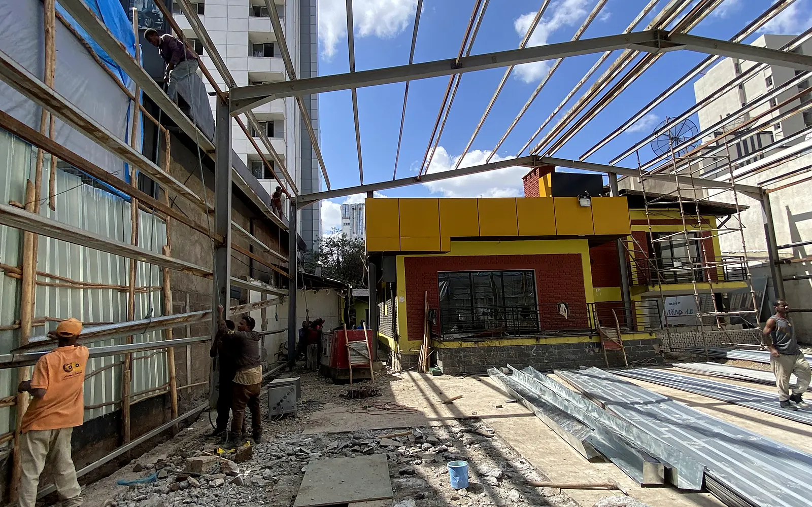 Roof steelwork being installed above an active interior workspace